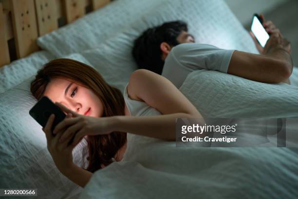 shot of a young couple using their cellphones in bed at morning back to back - russell crowe and wife danielle spencer separate after 9 years of marriage stockfoto's en -beelden