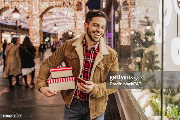 jeune homme dans le magasinage de noël - achat photos et images de collection