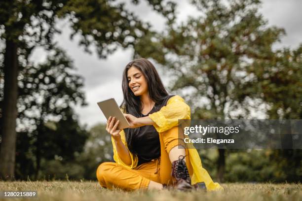 schöne frau lesen e-book auf digitalen tablet im freien - frau mit gelben regenmantel stock-fotos und bilder