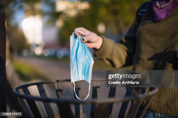 teenage girl throwing used protective mask into trash bin - throwing rubbish stock pictures, royalty-free photos & images