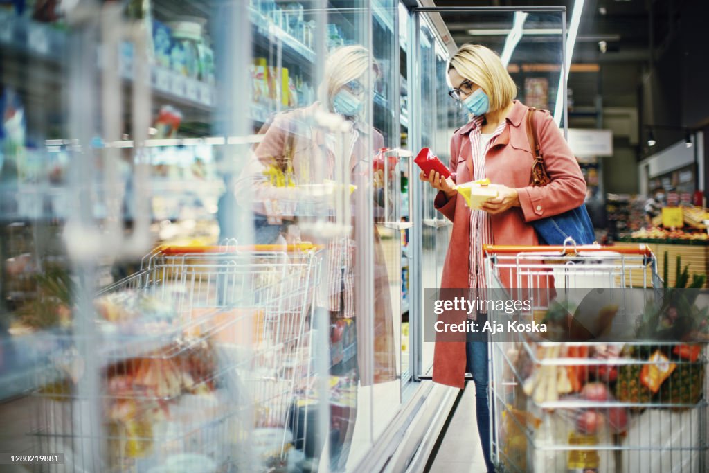 Woman choosing cheese in supermarket.