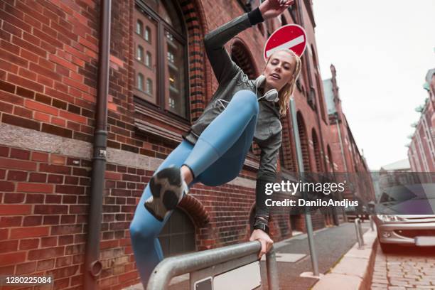 actieve vrouwelijke die parkour in een stad doet - freerunning stockfoto's en -beelden