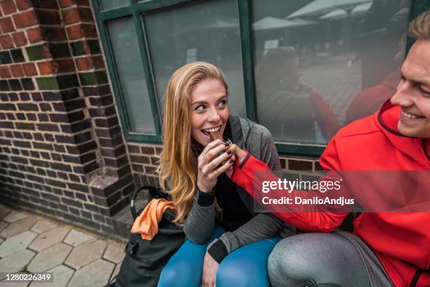 casal alegre esportivo fazendo pausa na calçada - couple chocolate - fotografias e filmes do acervo