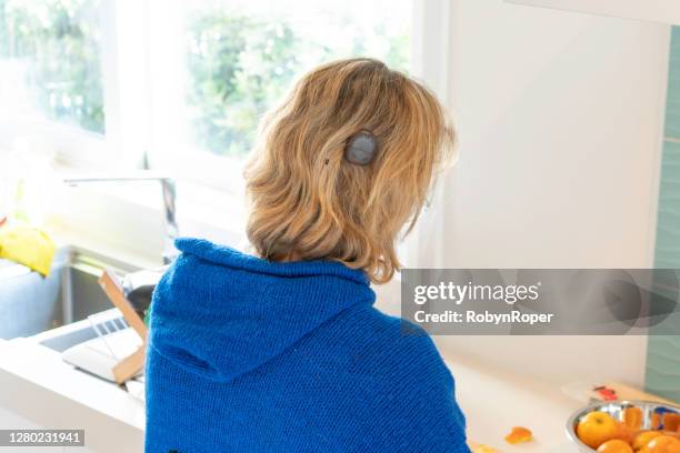 adult female with cochlear implant cuts fresh oranges on kitchen counter - cochlea implant stock pictures, royalty-free photos & images