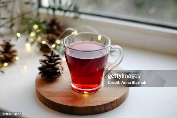 hot homemade winter drink in glass cup on window sill, pine cones and christmas decorations - glogg photos et images de collection