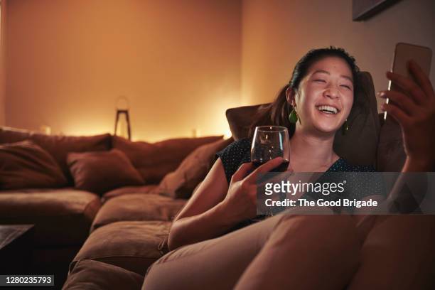 woman having video call on sofa at home - avoids fotografías e imágenes de stock