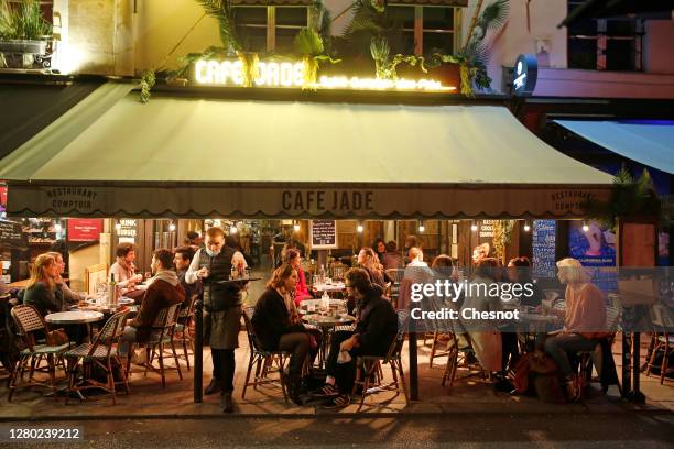 People enjoy a drink in a cafe terrace as French President Emmanuel Macron deploys curfew amid accelerating coronavirus epidemic on October 14, 2020...