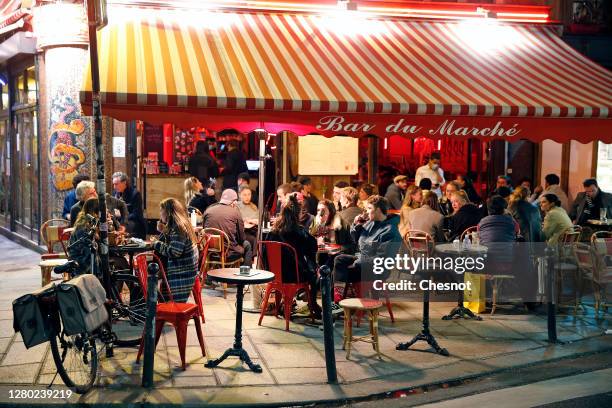 People enjoy a drink in a cafe terrace as French President Emmanuel Macron deploys curfew amid accelerating coronavirus epidemic on October 14, 2020...