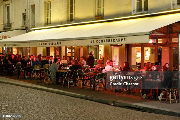 People enjoy a drink in a cafe terrace as French President Emmanuel Macron deploys curfew amid accelerating coronavirus epidemic on October 14, 2020...