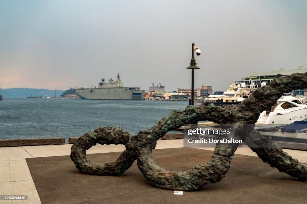 Navio de desembarque da Marinha Real Australiana e Royal Botanic Garden Sydney ao anoitecer na fumaça de vários incêndios florestais, Sydney, Austrália