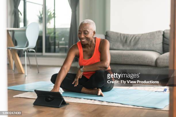 una donna anziana nera partecipa a una lezione di yoga online - esercizio fisico foto e immagini stock