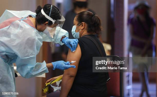 Nurse prepares to administer a flu vaccination shot to a woman at a free clinic held at a local library on October 14, 2020 in Lakewood, California....