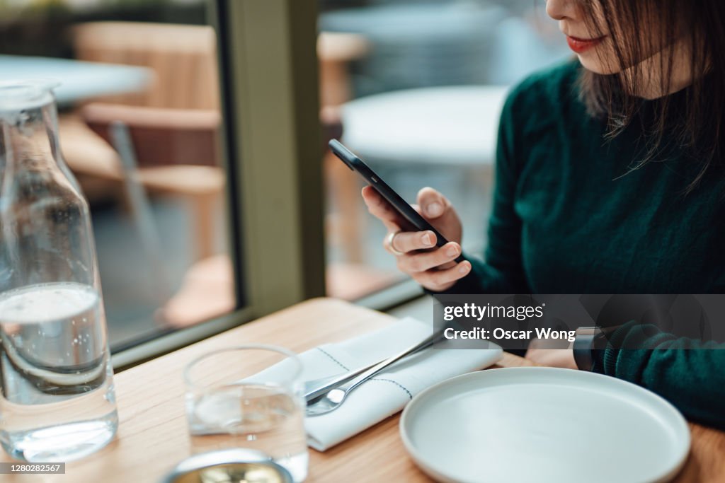 Young Woman Using Smart Phone While Relaxing At A Restaurant