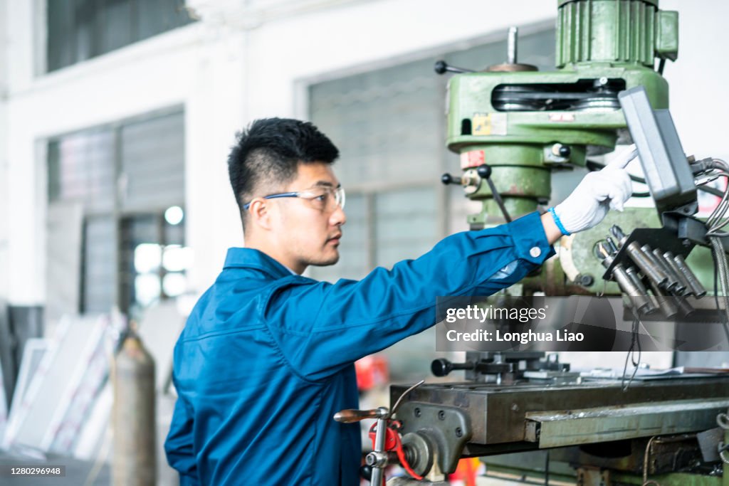 Machine Tools Worker An Asian Male Worker Operates A Machine Tool In A Factory High-Res ...