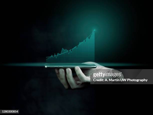 businessman holding a smart phone and showing holographic graphs and stock market statistics gain profits. concept of growth planning and business strategy. display of good economy form digital screen. - finanza ed economia foto e immagini stock