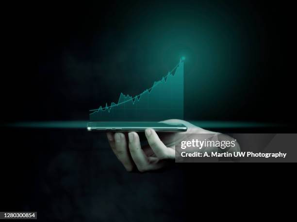businessman holding a smart phone and showing holographic graphs and stock market statistics gain profits. concept of growth planning and business strategy. display of good economy form digital screen. - digital health display stock pictures, royalty-free photos & images