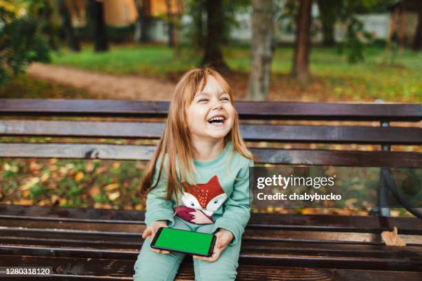 happy girl holding smart phone - children screen stock pictures, royalty-free photos & images