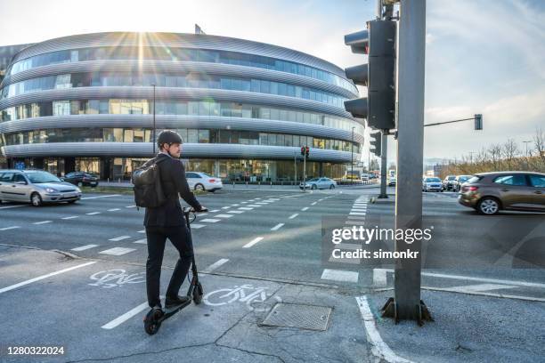 homme d’affaires attendant le feu de circulation avec son e-scooter - marquage de route photos et images de collection