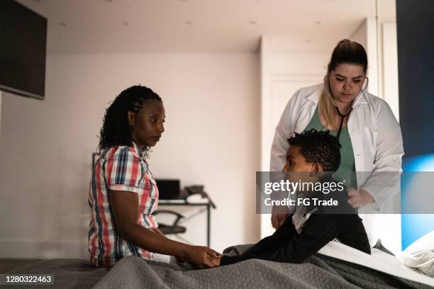 doctor using stethoscope listening to child patient breathing at his house - hot latin nights stock pictures, royalty-free photos & images