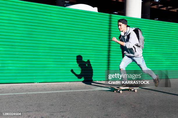 boy skating on the street on green background - boy skating stock pictures, royalty-free photos & images