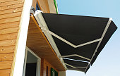 Outdoor high quality automatic sliding canopy retractable roof system, patio awning for sunshade of a modern wooden house.