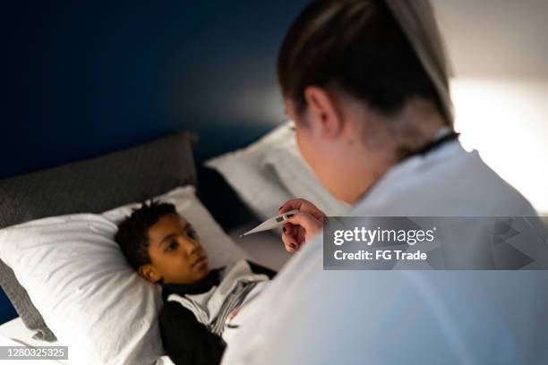 doctor taking temperature of child patient at visit in his house - hot latin nights stock pictures, royalty-free photos & images
