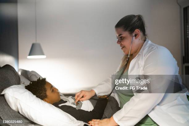 doctor examining child patient at visit in his house - hot latin nights stock pictures, royalty-free photos & images