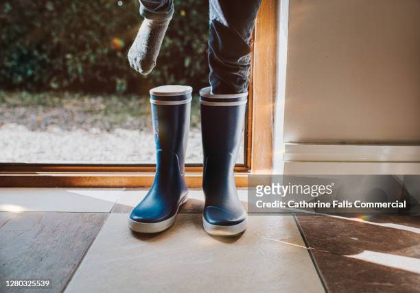 child putting on blue wellington boots - chaussettes sales photos et images de collection