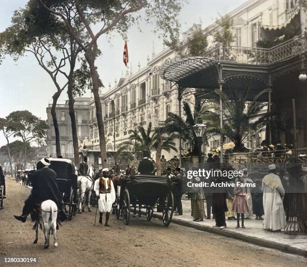 Colorized exterior view of traffic outside the Shepheard's Hotel and veranda, Cairo, Egypt, 1906.