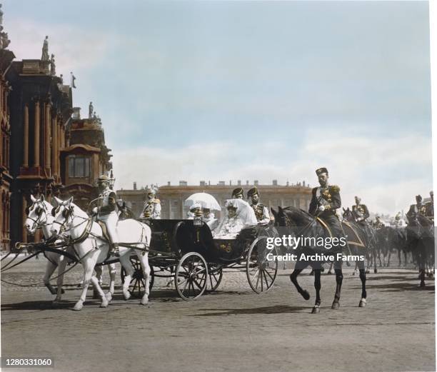 Colorized photo of Russian Tsar Nicholas II riding alongside a horse-drawn carriage transporting his wife, German-born Russian Tsarina Alexandra...