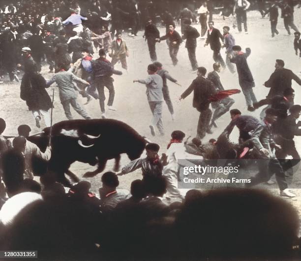 Colorized photo of men trying to evade charging bulls during the annual Running of the Bulls, held during the Festival of San Fermin, Pamplona,...