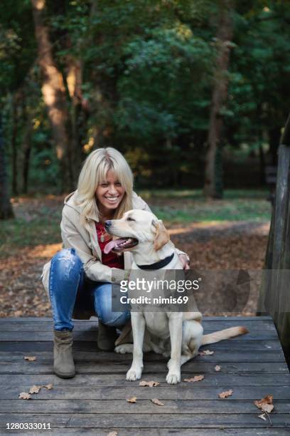 her dog make her happy - mature adult walking dog stock pictures, royalty-free photos & images
