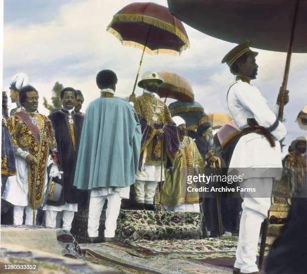 Colorized photo of Ethiopian Emperor Haile Selassie I in the royal enclosure during his coronation, Addis Ababa, Ethiopia, 1930. A man in a cape...