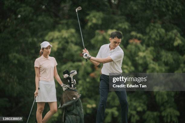 asian chinese male golfer teeing off and swing his driver club on the golf course - elite athlete stock pictures, royalty-free photos & images