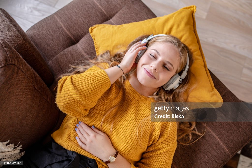 Joven mujer relajarse en casa y escuchar música