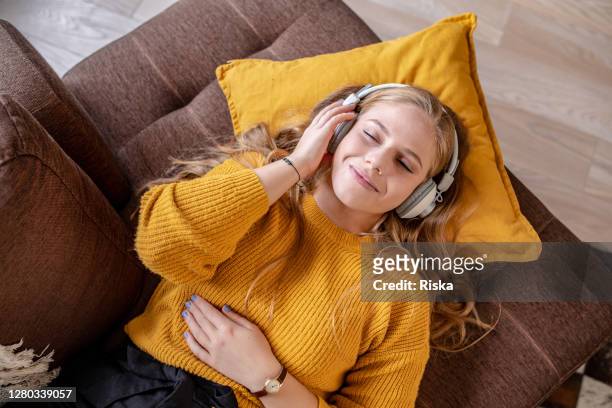 young woman relaxing at home and listening music - listening imagens e fotografias de stock