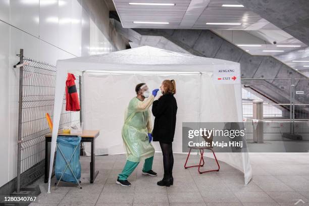 Member of the German Red Cross wears a PPE protective suit while taking a throat swab sample at a Covid-19 testing station set up at Berlin main...