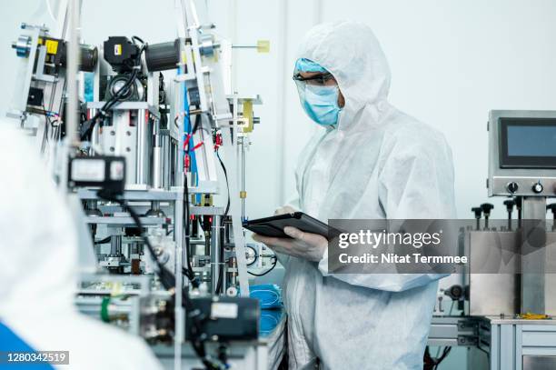 automated face mask production line in modern factory. an operator or engineer works at a machine by computer-aided engineering. - chemical manufacturing stock pictures, royalty-free photos & images