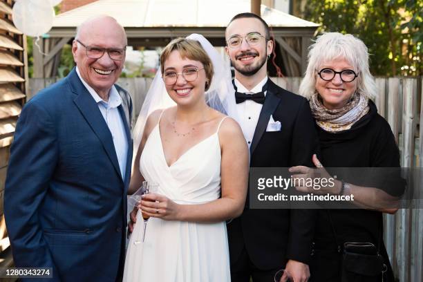 millennial newlywed couple posing with grandparents in backyard. - newly married stock pictures, royalty-free photos & images