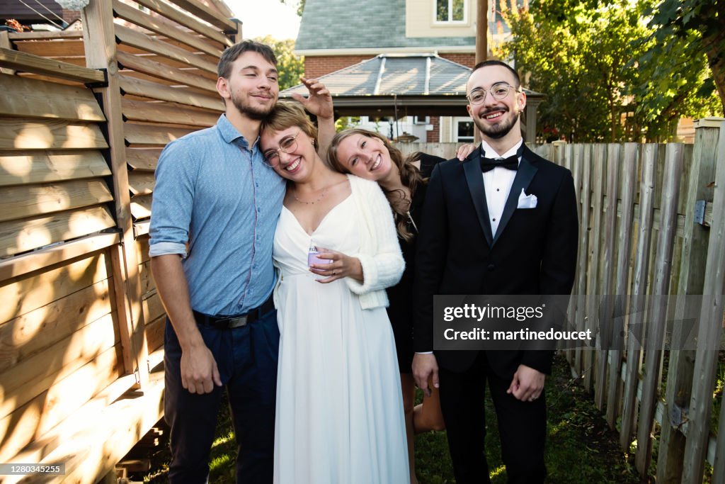 Millennial newlywed couple posing with brother and sister in backyard.