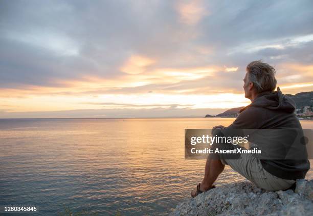 man looks out to sea from coastal area at sunrise - sunrise horizon stock pictures, royalty-free photos & images