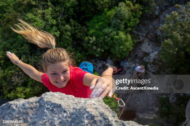 young woman climbs up mountain ledge - cliff ledge stock pictures, royalty-free photos & images