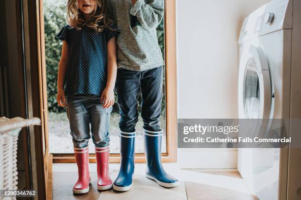 boy and a girl wearing wellies in a utility room - mud floor stock pictures, royalty-free photos & images