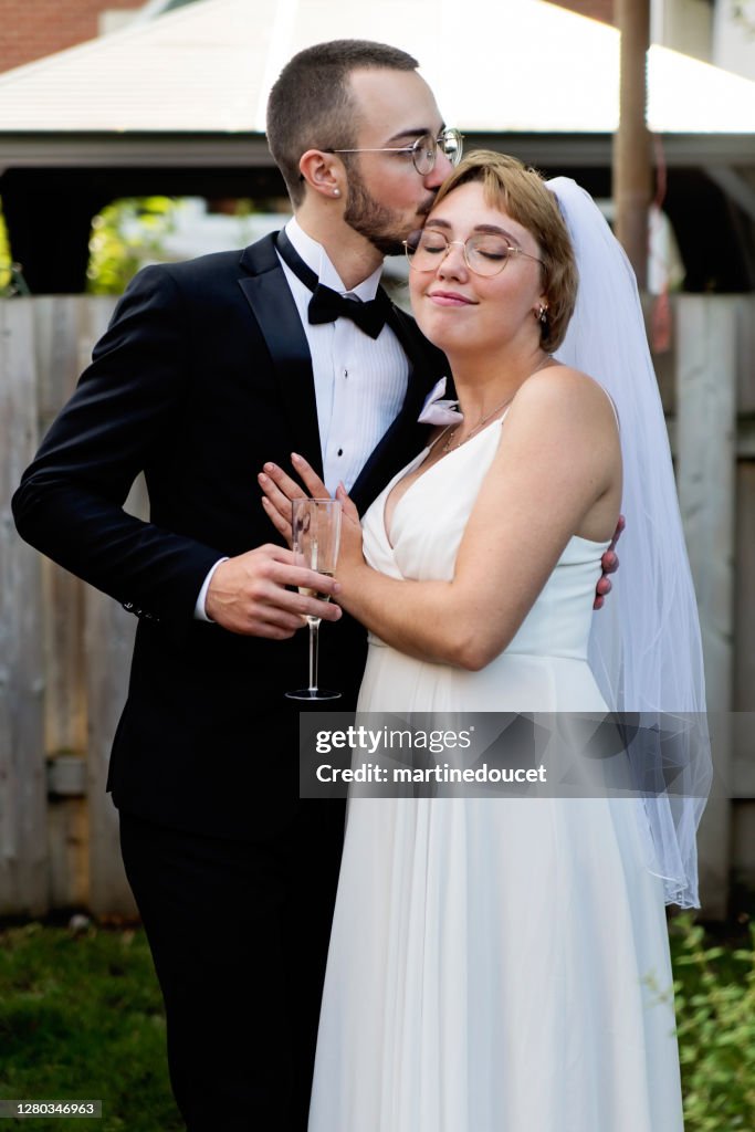 Millennial pareja recién casado posando en cóctel de boda en el patio trasero.