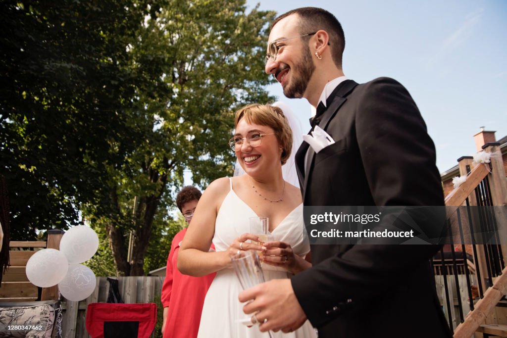 Casal recém-casado millennial no coquetel de casamento no quintal.