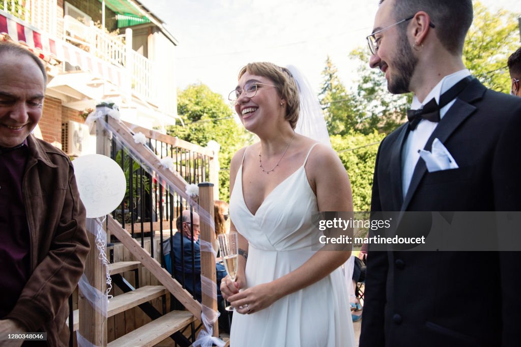 Millennial pareja recién casado en el cóctel de bodas en el patio trasero.