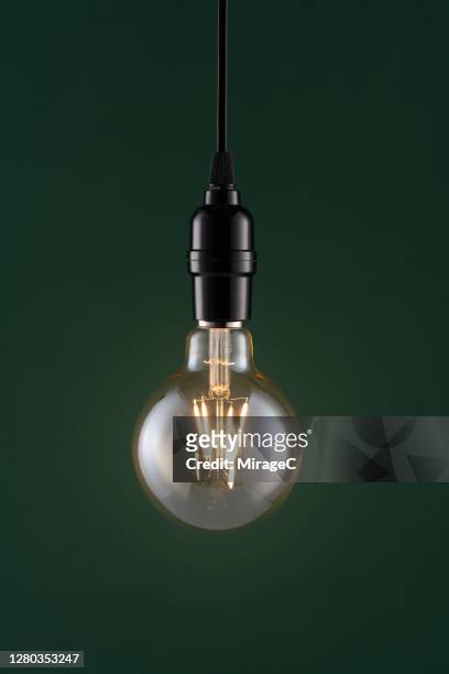 retro style light bulb on dark green - hanging lights stock pictures, royalty-free photos & images