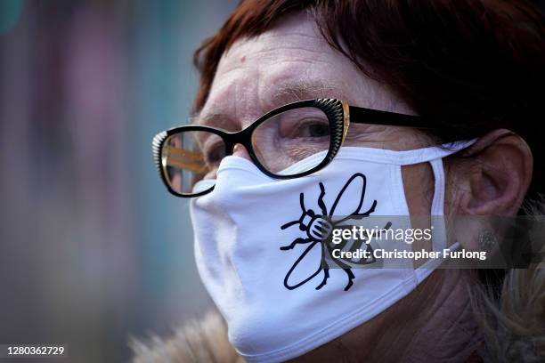 Woman wears a Covid-19 protection face mask with the Manchester Worker Bee motif as she walks through the city centre on October 15, 2020 in...