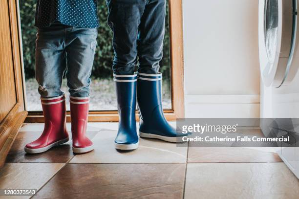 boy and a girl wearing wellies in a utility room - brother sister shower stock-fotos und bilder