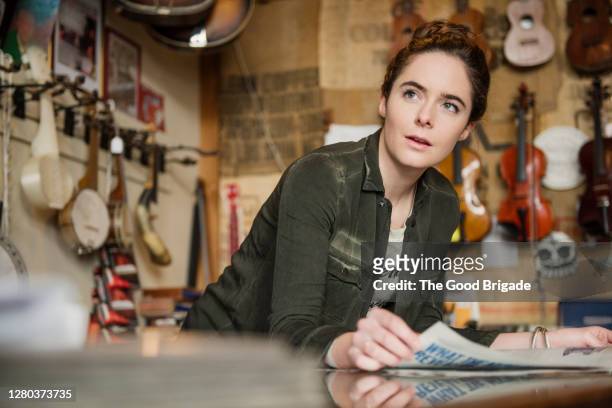 young woman working behind counter in music shop - music shop stock pictures, royalty-free photos & images
